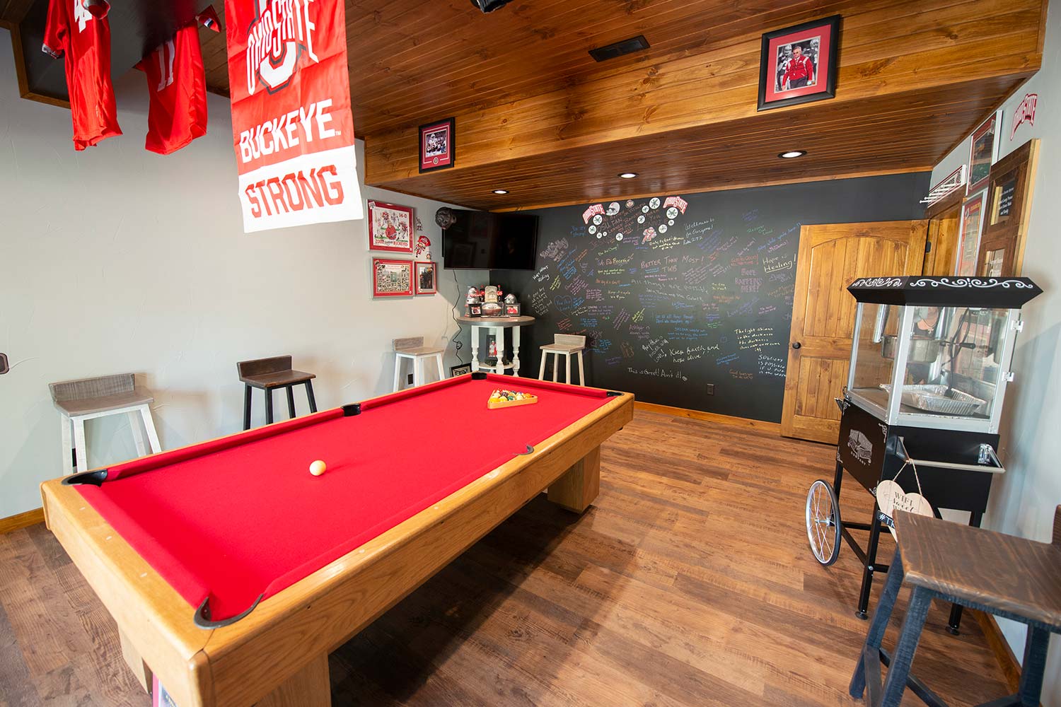 Game room with a pool table, popcorn machine, and a wall of testimonials in the background.