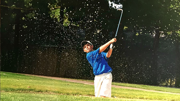 Tyler Bornstein golfing, hitting the ball out of a sand trap as a young man.